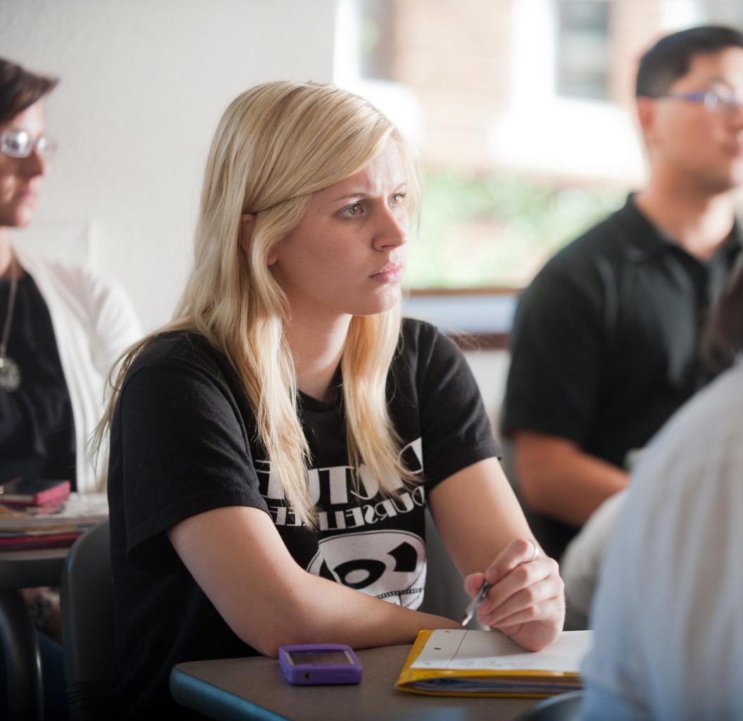 Young woman in classroom with pen and paper.