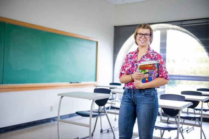 Teacher holding books in a classroom.