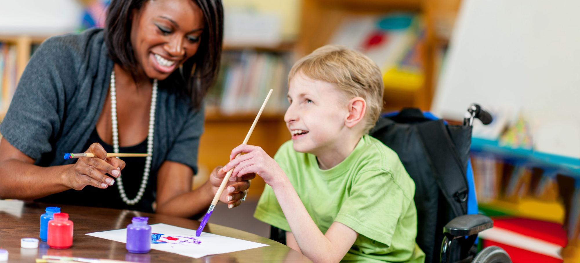 Special Education teacher interacting with student in a classroom. 